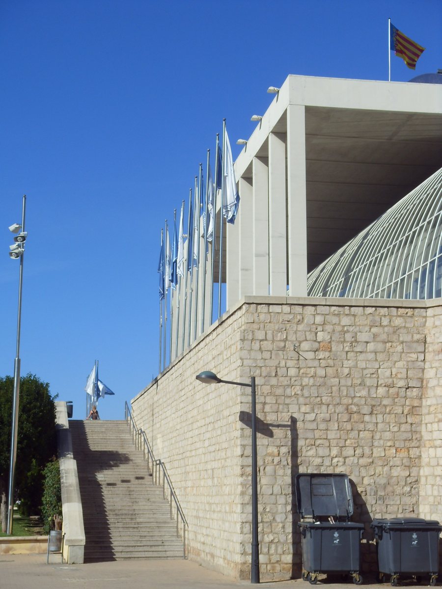 Cultural building in Valencia with a wide outdoor staircase and flags